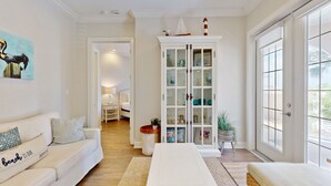 A spacious living room with a white sofa, a coffee table, and a cabinet with glass doors. - Designer Condo in Popular Palmilla | Close to Pool & Boardwalk (Port Aransas)