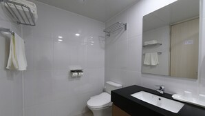 A modern bathroom with a white toilet, a black sink, and a mirror.