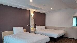 A hotel room with two single beds, a mirror, a wall-mounted light, and a window with curtains.