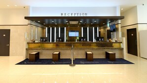A reception area with a 'RECEPTION' sign, a digital display, and a counter with a glass partition.