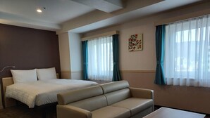 A hotel room with a bed, a sofa, a table, and two windows with curtains. - Toyoko Inn Changwon (Changwon)