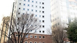 A tall, modern building with a grid of windows, surrounded by trees and other buildings. - Toyoko Inn Changwon (Changwon)