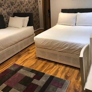 A hotel room with two single beds, a wooden floor, and a patterned rug. - Msk Hotel 82 London (London)