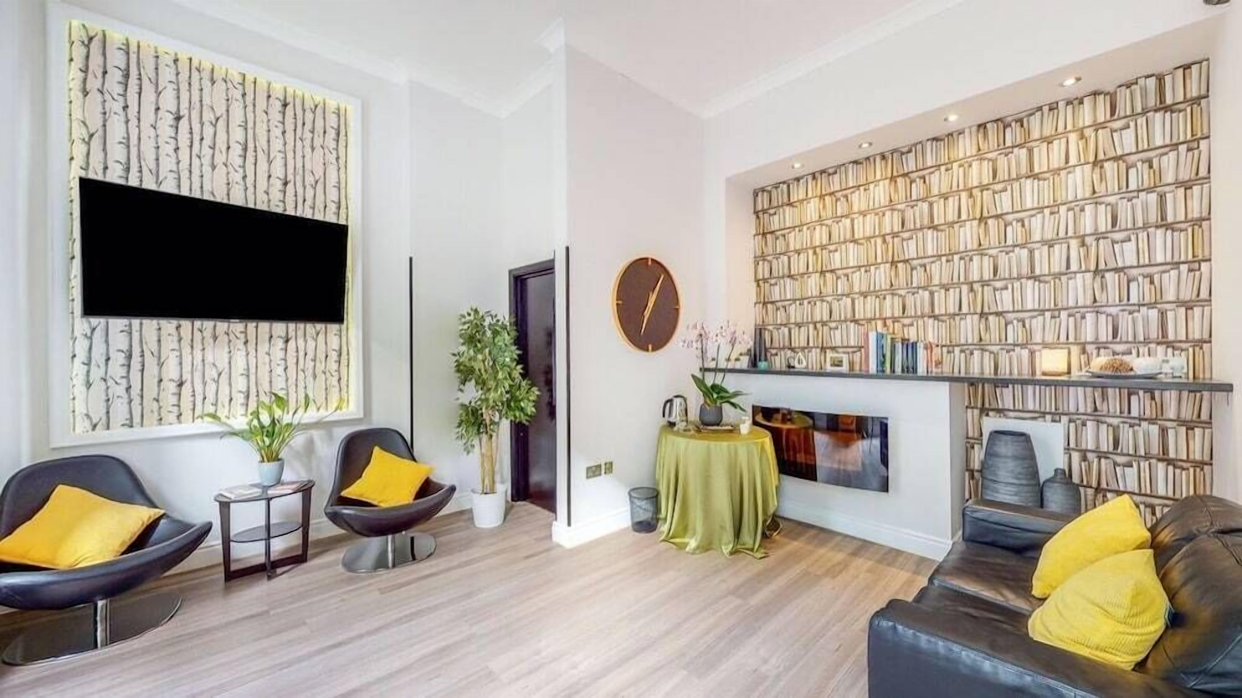 A modern living room with a fireplace, a bookshelf, and a flat-screen TV.
