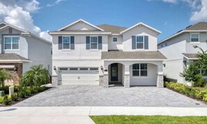 Stylish entrance with a central door and porch area, surrounded by beautifully maintained gardens.