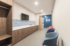 A modern bathroom with a tiled backsplash, a wooden vanity, a sink, and a toilet. There are two chairs and a washing machine. - Holiday Inn Express Shanghai Xuhui Binjiang (Shanghai)