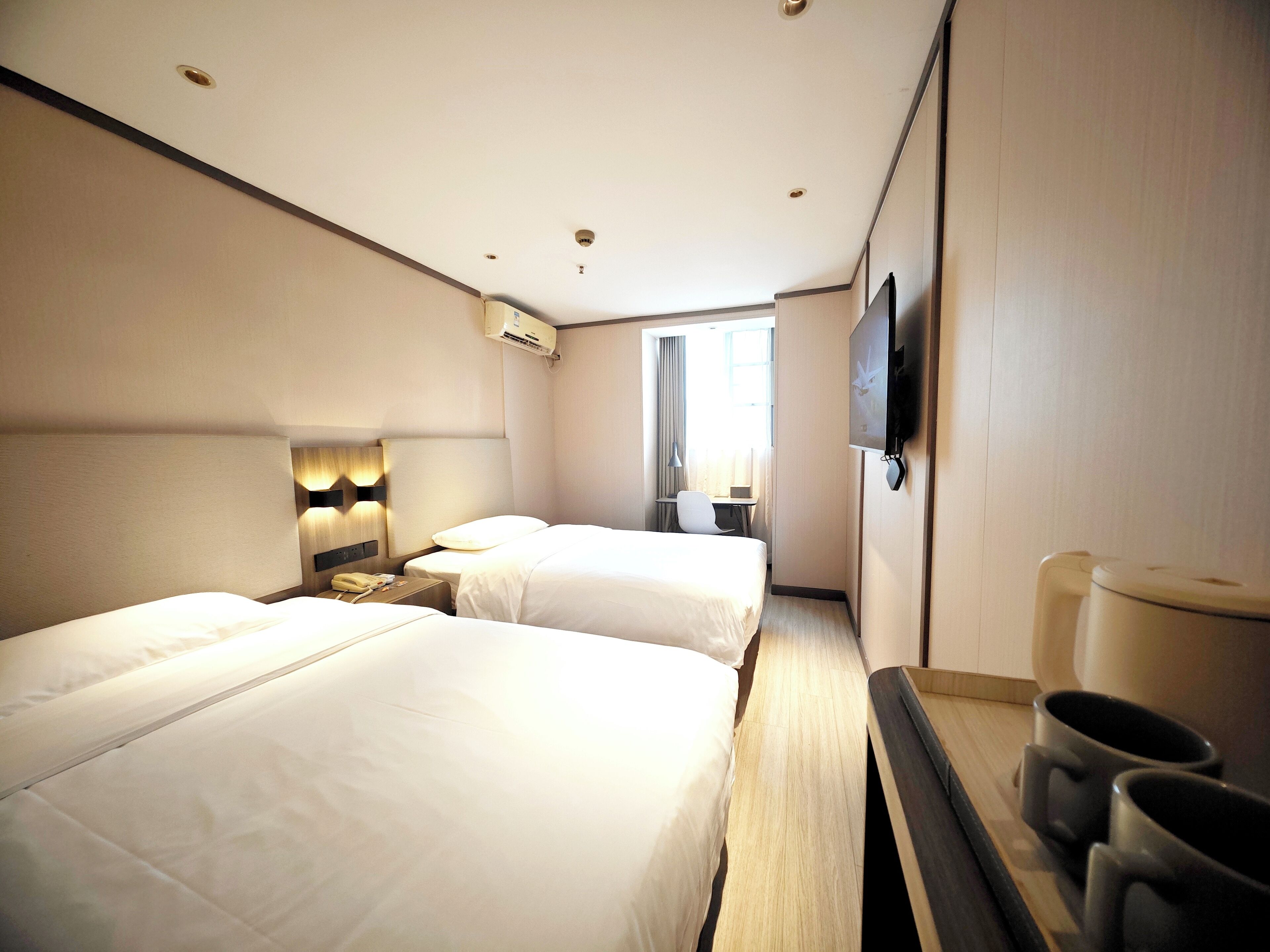 Une chambre d’hôtel avec deux lits, un bureau, une télévision et un coin café.