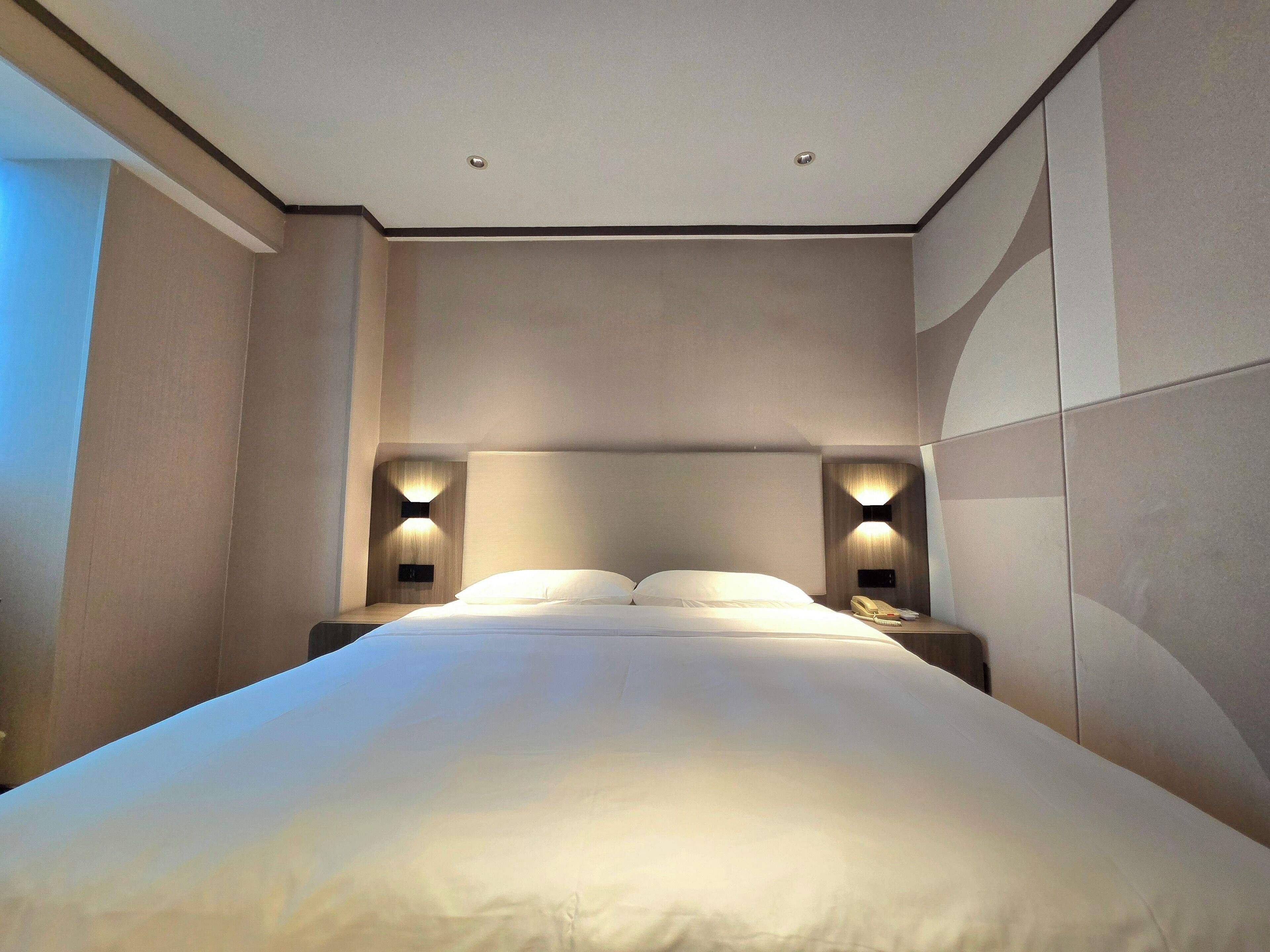 A hotel room with a large bed, two bedside tables with lamps, and a neutral color scheme.