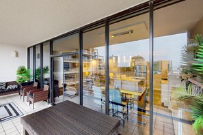 A modern hotel room with a large sliding glass door leading to a balcony. Inside, there is a sofa set and a dining table. - Gulf & Gather | 2 Resort-View Balconies | Heated Pools, Tennis, Beach Access (South Padre Island)