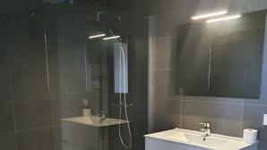 A modern bathroom with a glass-enclosed shower, a white vanity, and a large mirror. - Superb T2 apartment with a beautiful view of the sea and the Bloody Islands (Grosseto-Prugna)
