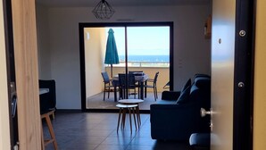 A modern living room with a large sliding glass door leading to a balcony with a view of the sea. - Superb T2 apartment with a beautiful view of the sea and the Bloody Islands (Grosseto-Prugna)