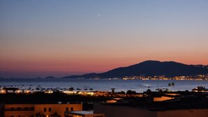 A coastal cityscape at dusk with buildings and boats along the waterfront. - Superb T2 apartment with a beautiful view of the sea and the Bloody Islands (Grosseto-Prugna)