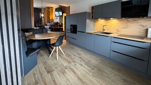 A modern kitchen with grey cabinets, a wooden dining table, and a built-in oven. - Only 100 m to the beach, apartment with balcony - App. Eldena FeWo 15 - Apartments (Middelhagen)