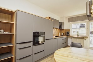 A modern kitchen with built-in appliances, a dining table, and a window with a view. - Just 100 m from the beach, apartment with a balcony - Apt. Eldena FeWo 15 - Apartments (Middelhagen)