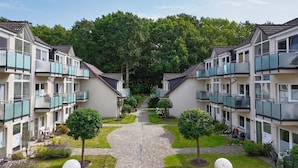 A row of modern apartment buildings with balconies, a central pathway, and well-maintained greenery. - Only 100 m to the beach, apartment with balcony - App. Eldena FeWo 15 - Apartments (Middelhagen)