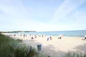 A beach with several beach chairs and umbrellas, a trash bin, and a person sitting on the sand. - Just 100 m from the beach, apartment with a balcony - Apt. Eldena FeWo 15 - Apartments (Middelhagen)