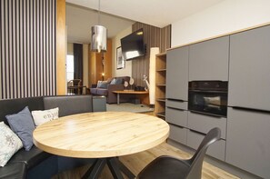 A modern kitchen with grey cabinets, a round wooden table, and a built-in oven. - Just 100 m from the beach, apartment with a balcony - Apt. Eldena FeWo 15 - Apartments (Middelhagen)
