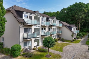 A multi-story residential building with balconies, a paved driveway, and surrounding greenery. - Just 100 m from the beach, apartment with a balcony - Apt. Eldena FeWo 15 - Apartments (Middelhagen)