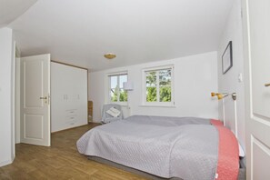 A bedroom with a bed, a wardrobe, a desk, and a window.