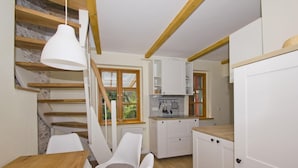 Una cucina moderna con mobili bianchi, un tavolo di legno e una scala con travi in legno.