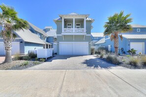 A two-story house with a garage, a balcony, and a driveway leading to the entrance. - Ocean-view paradise with pool, gym, gourmet kitchen & beautiful new furniture (Port Aransas)