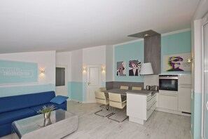 A modern apartment with a living area, a dining space, and a kitchenette.