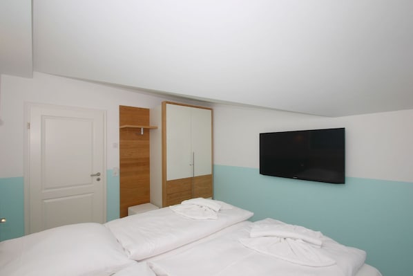 A bedroom with a bed, a wardrobe, a mirror, and a TV.