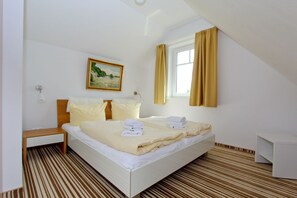 A hotel room with a bed, a nightstand, a painting, and a window with curtains. - Beachfront vacation rental with a balcony, access to the pool and sauna - Rex Rugia H-1010 - (Göhren)