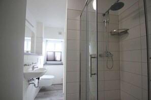 Une salle de bain moderne avec une douche à parois de verre, un lavabo blanc et des toilettes.
