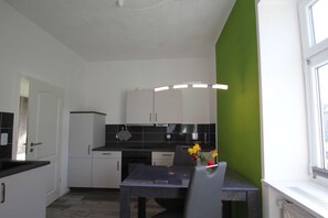A compact kitchen with white cabinets, a black countertop, and a green accent wall.