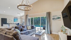 A spacious living area with a large sofa set, a dining table, and a kitchen in the background. - Pool Home Near Beaches and Downtown 5th Ave. (Naples)