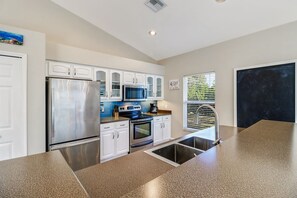 A modern kitchen with white cabinets, stainless steel appliances, and a granite countertop.
