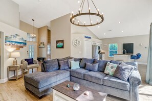 A modern living room with a sectional sofa, a wooden coffee table, and a chandelier. - Pool Home Near Beaches and Downtown 5th Ave. (Naples)
