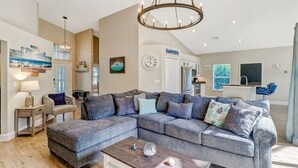 A modern living room with a sectional sofa, a coffee table, and a chandelier. - Pool Home Near Beaches and Downtown 5th Ave. (Naples)