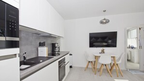 A modern kitchen with a built-in oven, a coffee maker, and a dining area with a table and chairs. - Modern vacation apartment with private terrace - Haus Inselwind FeWo MEERküste - (Gager)