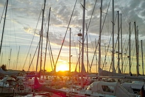 A marina with multiple sailboats docked, featuring masts and rigging, under a sunset sky. - Modern vacation apartment with private terrace - Haus Inselwind FeWo MEERküste - (Gager)