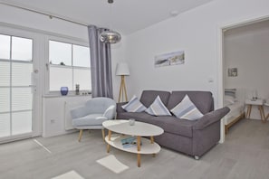 A modern living room with a grey sofa, a blue armchair, and a round coffee table.