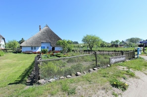 A traditional thatched-roof house with a sign reading "Pfarrwitwenhaus" in front. - Modern vacation apartment with a private terrace - Haus Inselwind FeWo MEERstille - (Gager)