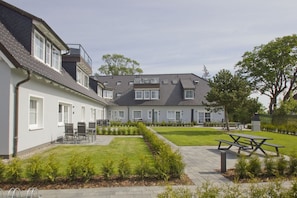 A residential building with a courtyard, outdoor seating, and a well-maintained lawn. - Modern vacation apartment with a private terrace - Haus Inselwind FeWo MEERstille - (Gager)