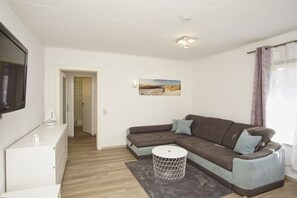 Una sala de estar moderna con un sofá modular, una mesita redonda y un televisor montado en la pared.