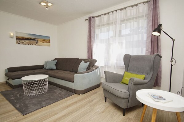 A modern living room with a sofa, armchair, small round table, and a floor lamp.