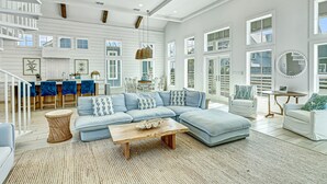 A spacious living room with a light blue sectional sofa, a wooden coffee table, and a dining area with a blue tablecloth. - Stunning Palmilla Beach home with gulf views, private pool, and golf (Port Aransas)