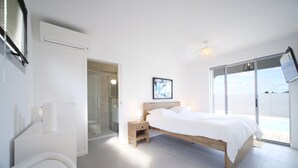 A modern bedroom with a large bed, a glass shower, and a view of the sea. - Architect designed villa for 8 with swimming pool (Saint François)