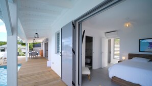 A bedroom with a large bed, a wooden deck, and a view of the outdoors. - Architect designed villa for 8 with swimming pool (Saint François)