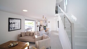 A modern living room with a sofa, a dining table, and a staircase. - Architect designed villa for 8 with swimming pool (Saint François)