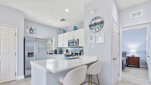A modern kitchen with a central island, stainless steel appliances, and a dining area with bar stools.