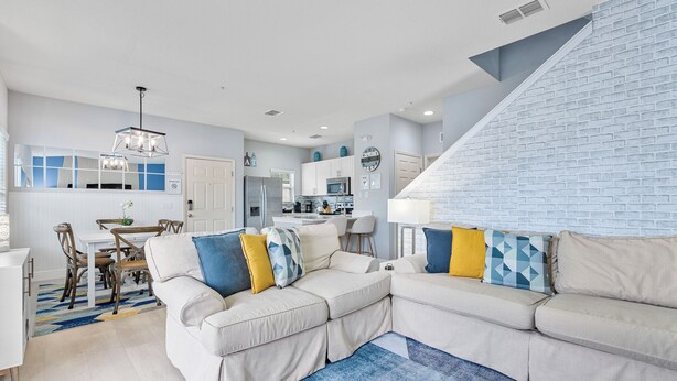 A modern living room with a sectional sofa, a dining area, and a kitchen in the background.