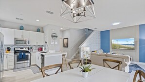 A modern kitchen with white cabinets, stainless steel appliances, and a dining area with a white table and chairs.