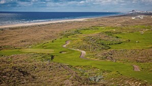 A golf course with a view of the ocean and a distant cityscape. - Luxe Palmilla townhome with resort pool & golf - walk to beach (Port Aransas)
