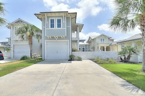 A two-story residential building with a garage, a covered porch, and a well-maintained lawn.